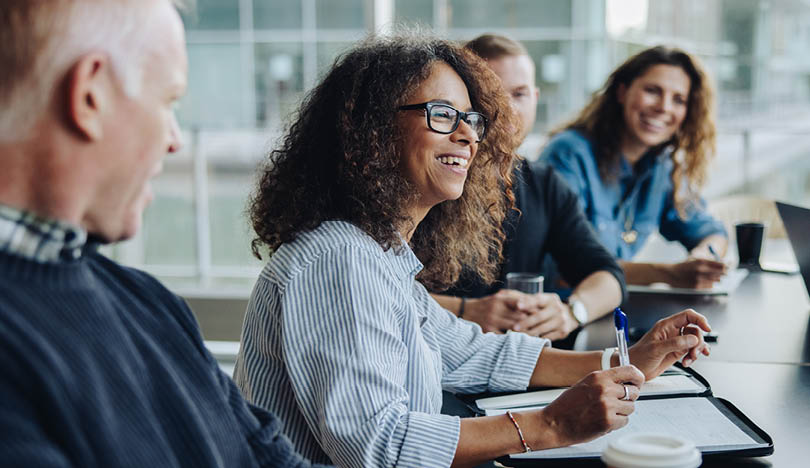 Multi-ethnic business people smiling during a meeting in conference room. Team of professionals having meeting in boardroom.
