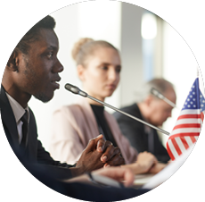 Side view of African businessman performing during conference he sitting at the table and speaking into the microphone